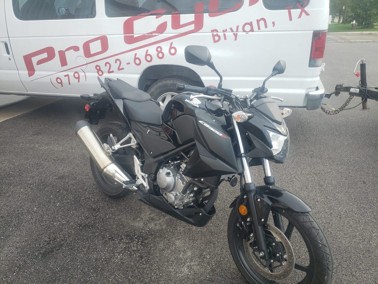A Honda CB300F parked beside the lettered Pro Cycle shop van outside the Bryan shop